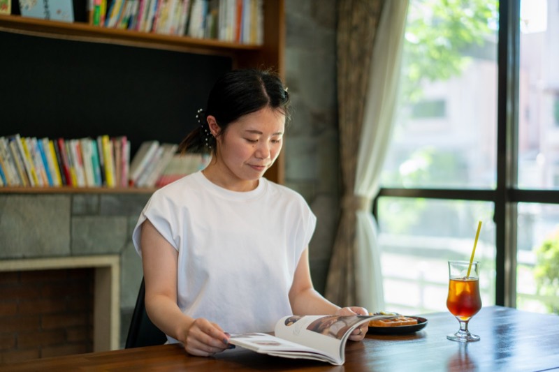 カフェの席で、アイスティーを横に雑誌を読む女性