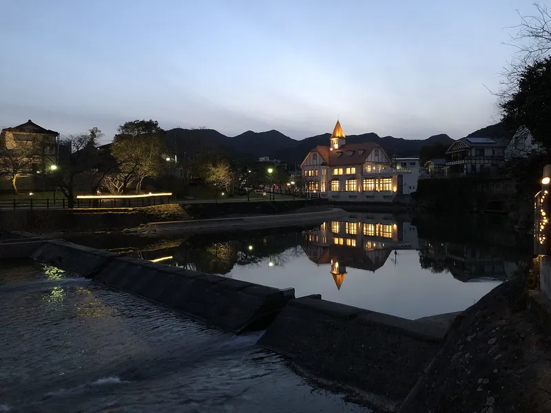 夕暮れの川と、明かりのともったシーボルトの湯