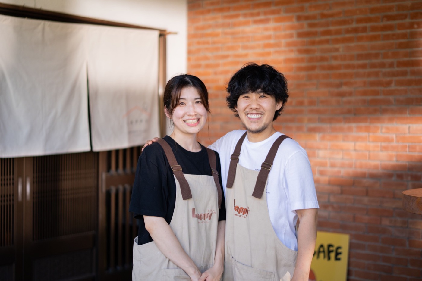 LAPPY CAFEの入口の前に立つ、大久保尚弥と佳鈴