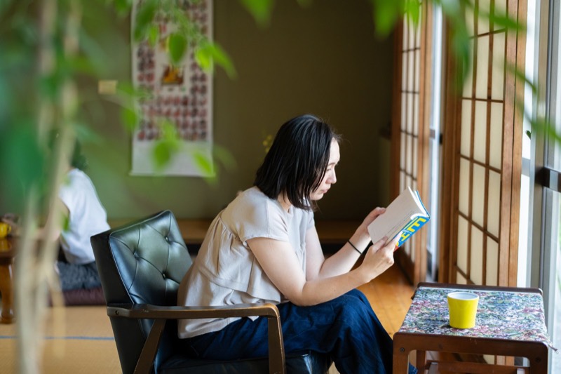 宿の窓辺の椅子で、本を読んでくつろぐ様子