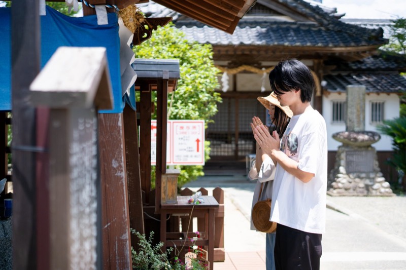 温泉街の神社の境内で、手を合わせてお参りする人