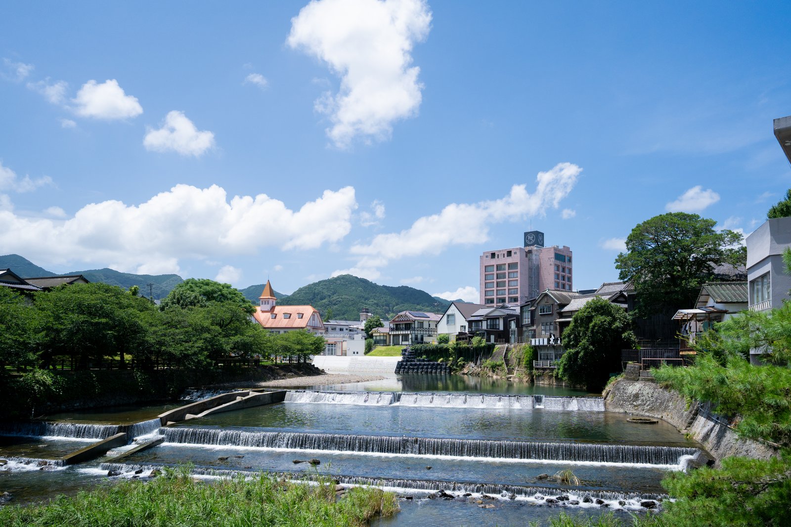 青空の下を流れる嬉野川と、川沿いに並ぶ温泉街の建物